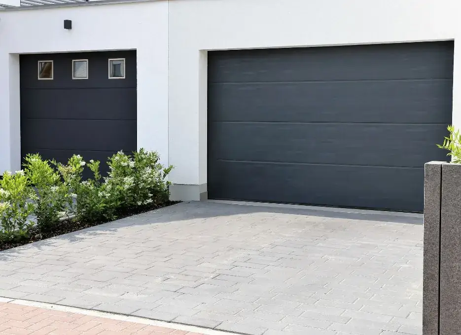 Newly installed modern black garage door on a white home
